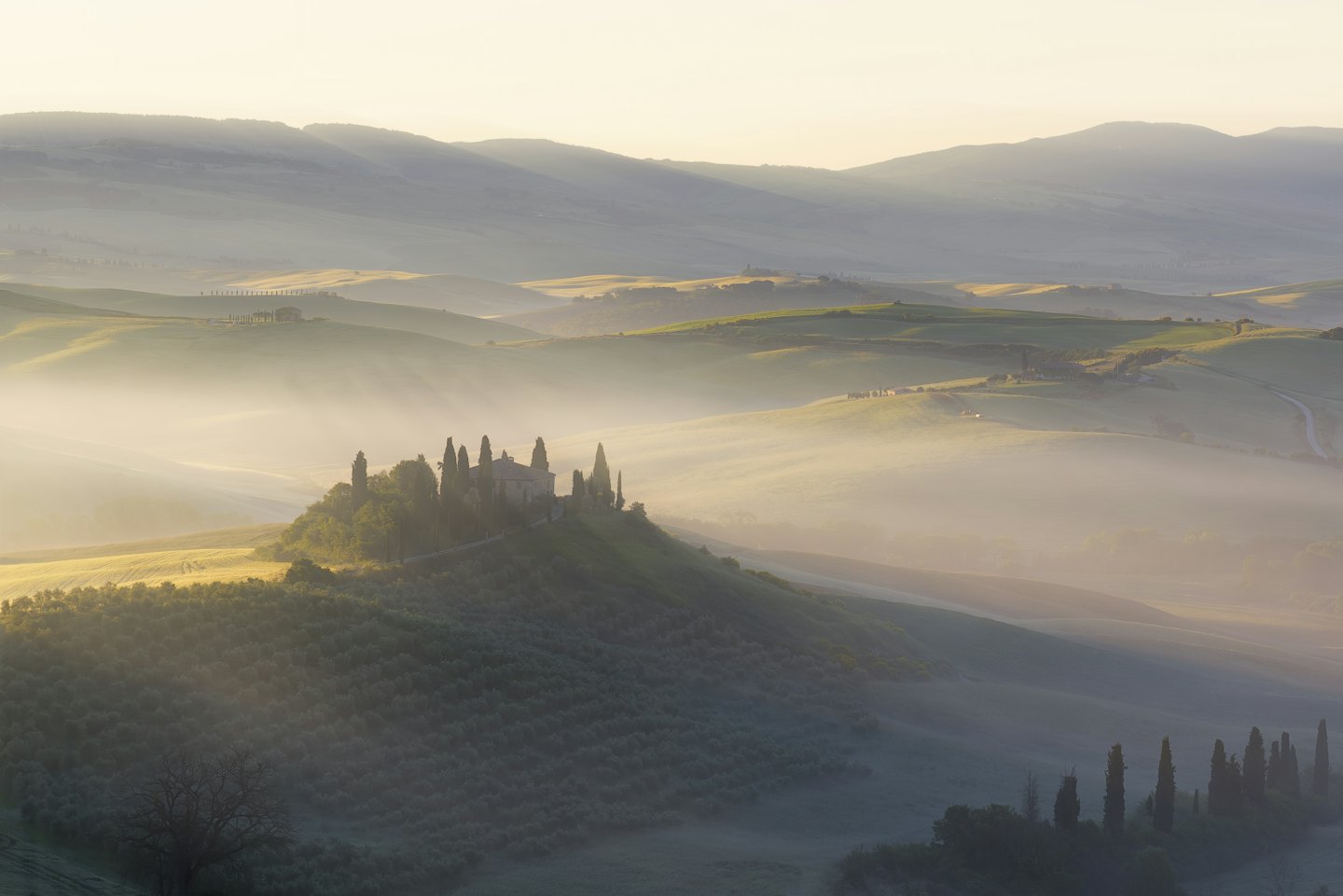 Una casa colonica su una collina nebbiosa circondata da colline.