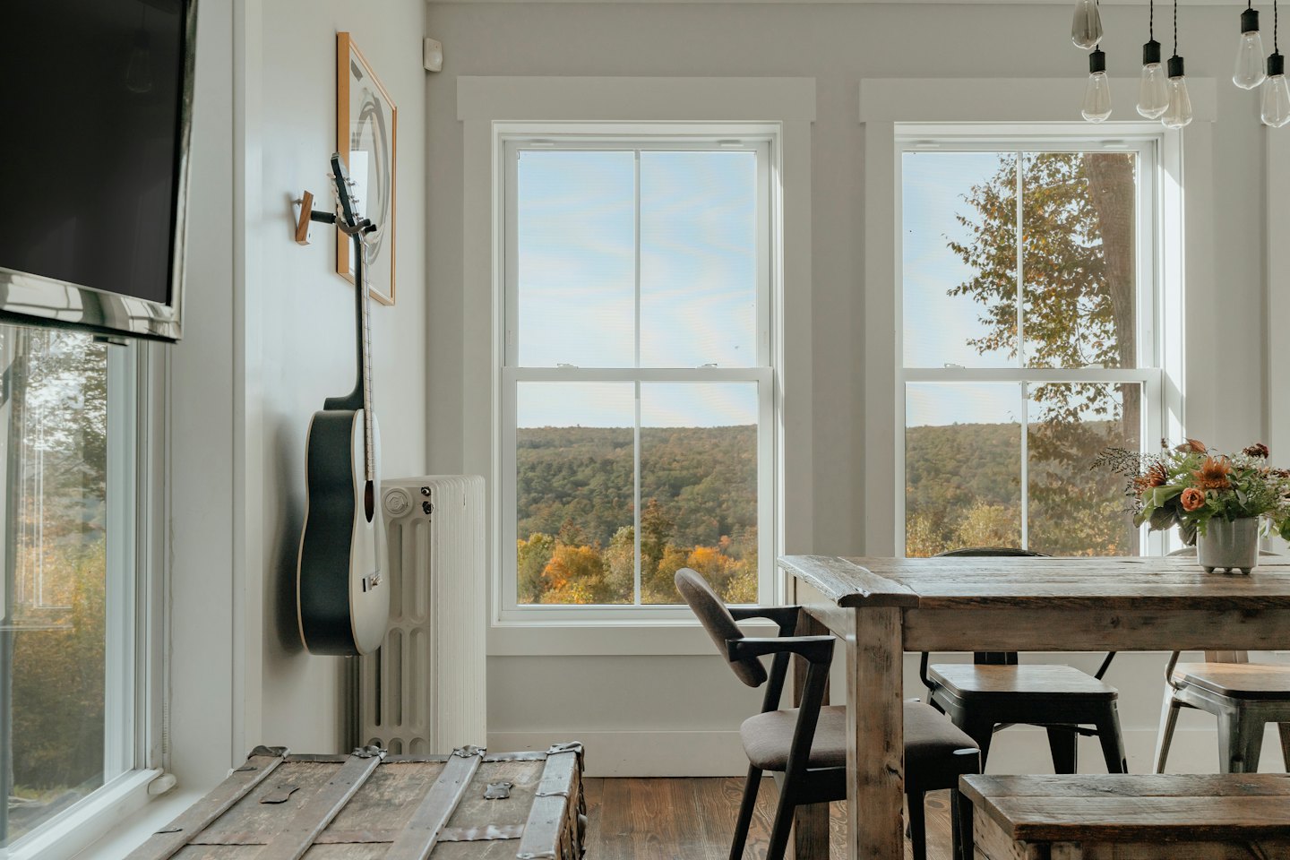 Sala da pranzo con vista sulla foresta autunnale e chitarra acustica.